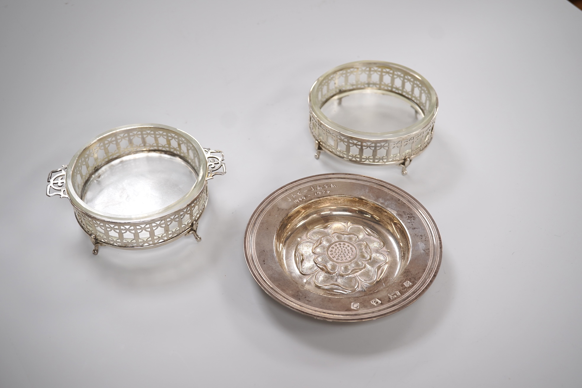 A 1970's silver 'Tudor Rose' dish, by Asprey & Co Ltd, diameter 11.8cm, together with a pair of George V silver mounted glass butter dishes.